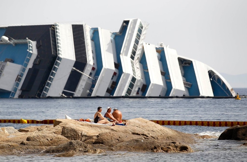 Tourists sunbathing next to the Costa Concordia